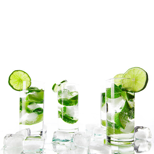 Party mojito cocktails with lime and mint ice cubes isolated on white