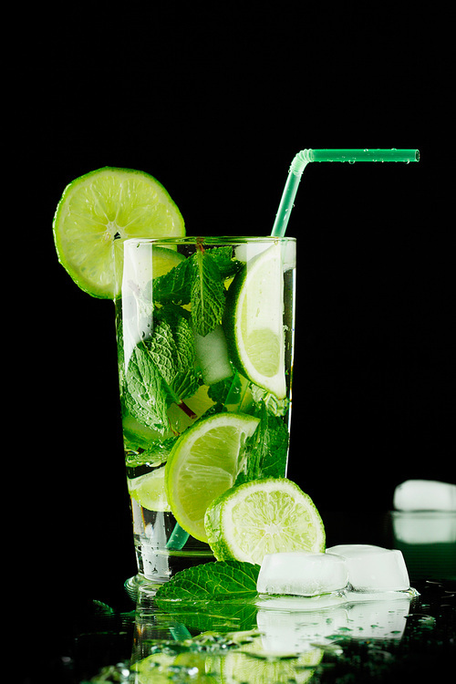 Mojito cocktail with lime, mint and ice on black background