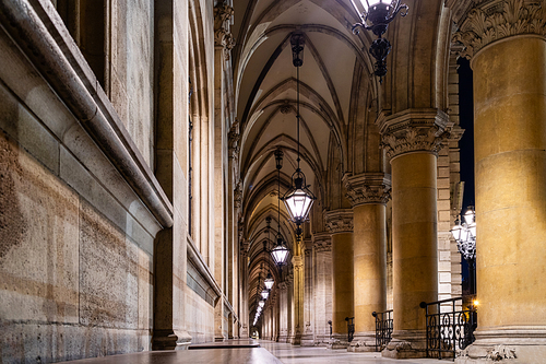 Stone arched perspective with ancient columns and vaulted ceiling with hanging old lamps in the temple in Vienna, Austria.