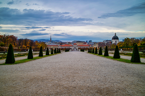 Wonderful landscape with wide main walking alley before Unteres Belvedere with regular planting of trees and plants in Vienna, Austria on a background of cloudy sky.