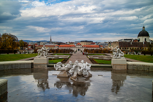 Historic landscape of fountain with ancient sculptures and statues in baroque style before Schloss Belvedere Palace in Vienne, Austria on a background of cloudy autumn sky.
