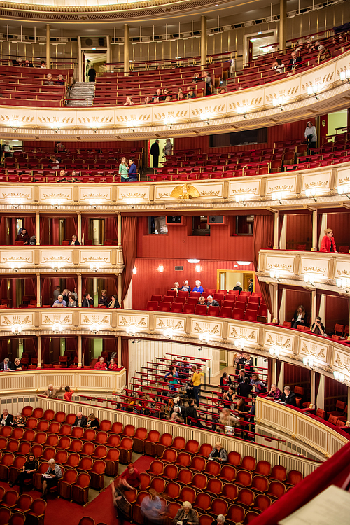 Beautiful and rich decoration of interior the Vienna State Opera auditorium with parterre and balconies and people before starting performance in Vienna, Austria.