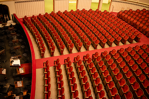 Wonderful view of the theatre concert hall of Vienna State Opera auditorium in Vienna, Austria - empty parterre with red seats in the rows without people and part of the orchestra pit.