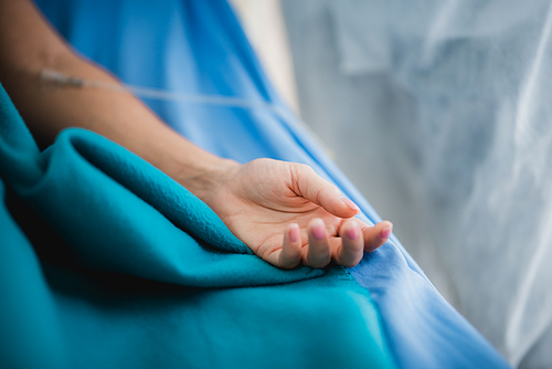 Close up  a patients hand, in an  room at hospital surgery room theater with the doctor and medical office staff