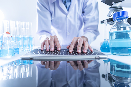 Portrait of confident scientist working on laptop in chemical laboratory