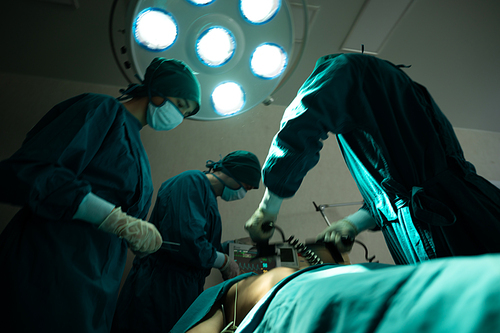 professional surgery team in the operating room, urgent surgery. Professional smart intelligent surgeons standing near the patient and performing an operation while saving his life