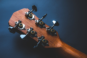 Acoustic guitar, music instrument resting against a dark black background with copy space, Close-up of wooden classic guitar