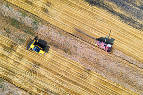 Aerial view of combine harvester is harvesting wheat at sunset in summer. Agriculture. Landscape with harvesters working on the yellow wheat field. Top view of agricultural machine and ripe wheat