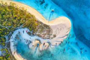 Aerial view of the fishing boats on tropical sea coast with white sandy beach at sunset. Summer holiday in Zanzibar, Africa. Landscape with boats, yachts, green trees, clear blue water. Top view