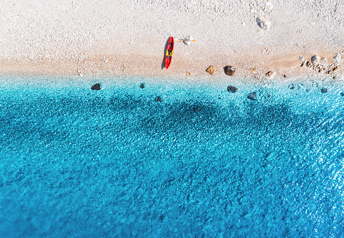 Aerial view of empty sandy beach with red canoe, sea coast with transparent blue water in sunny bright day in summer. Travel in Croatia. Top view of boats. Landscape with kayaks at sunset. Travel