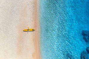 aerial view of empty sandy beach with yellow canoe, sea coast with transparent blue water in sunny bright day in summer. travel in croatia. top view of boats. landscape with kayaks at . travel
