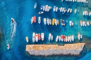Aerial view of colorful boats and yachts in port in blue sea at sunset. Summer landscape with beautiful motorboats in harbor, pier, transparent water in Dubrovnik. View from above of harbour. Travel
