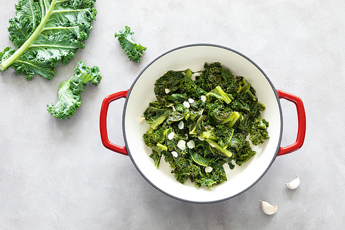 Sauteed kale with garlic in cast iron pan on kitchen table, healthy food concept, superfood