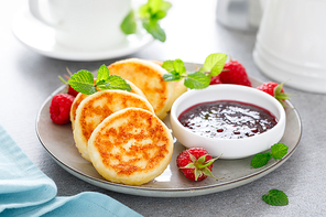 Cottage cheese pancakes, sweet curd fritters with berries, syrniki with jam and fresh raspberry on breakfast table