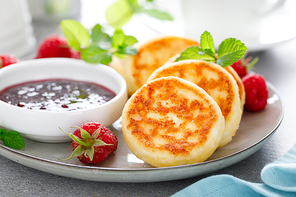 Cottage cheese pancakes, sweet curd fritters with berries, syrniki with jam and fresh raspberry on breakfast table