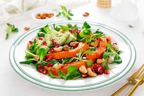 Fresh vegetable salad with lambs lettuce, baked butternut squash or pumpkin, avocado, pomegranate, cashew and almond nuts. Healthy vegetarian food concept.