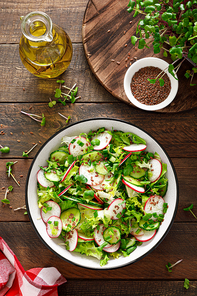 Radish and cucumber salad with fresh green onion in bowl, Top view