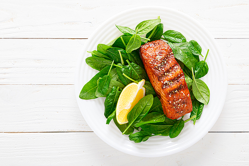 Salmon fish fillet grilled and fresh spinach salad on plate for lunch. Top view
