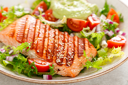 grilled salmon fish fillet and fresh green lettuce  tomato salad with avocado guacamole