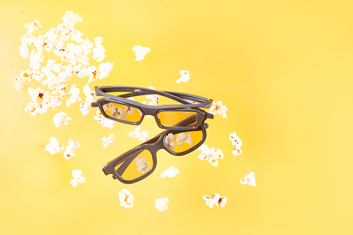 popcorn and two 3d glasses over yellow background, movie and cinema concept