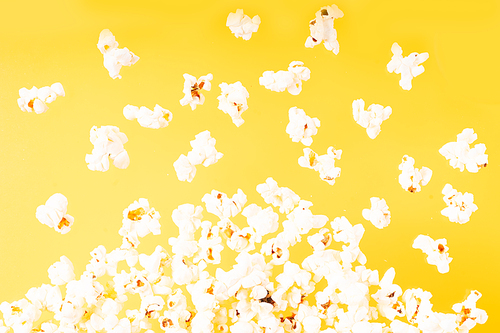 Scattered fresh popcorn falling over yellow background
