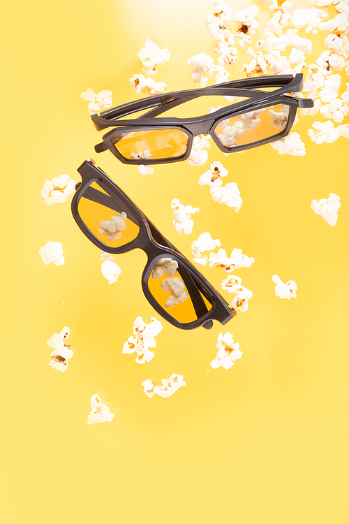 popcorn and two pairs of 3d glasses over yellow background, movie and cinema concept