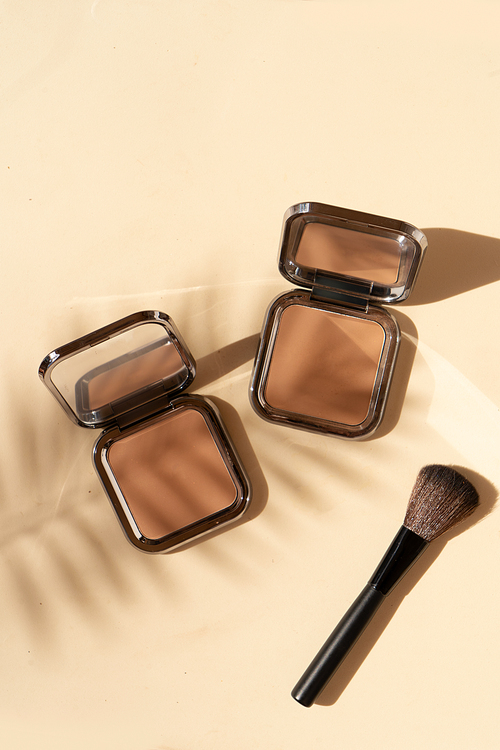 Minimal modern cosmetic scene with make up brushe, bronzer and palm shadow overlay, top view