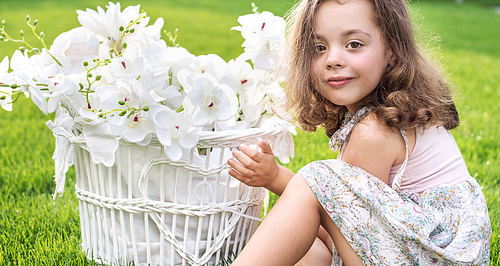 Portrait of a cute child holding a wicker basket with white plants