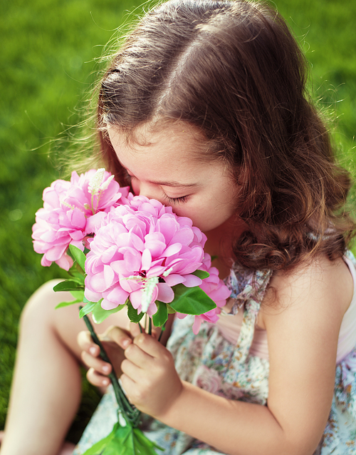 Pretty and cute child holding and sniffing flowers