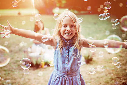 Cheerful, little girl enjoying bubble blowing