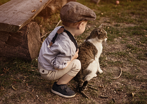 Cute, little boy enjoying an autumn warm day with a cat