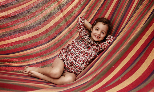 Cute little girl realxing on a colorful hammock