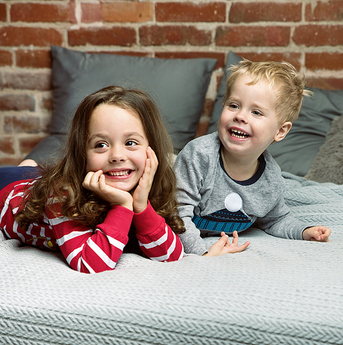 Portrait of joyful siblings relaxing in bedroom