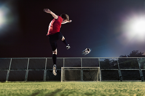 Athlete kicking soccer ball towards goal