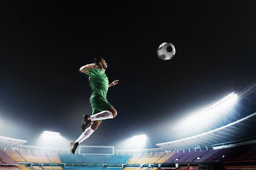 Athlete heading soccer ball in stadium