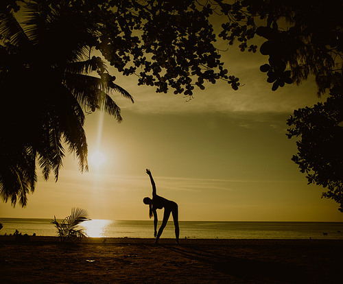 Flexible woman training on a tropical beach