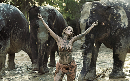 Sensual tamer playing with elephants in clay