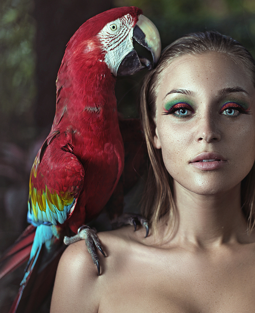 Beautiful young woman with a parrot on a shoulder