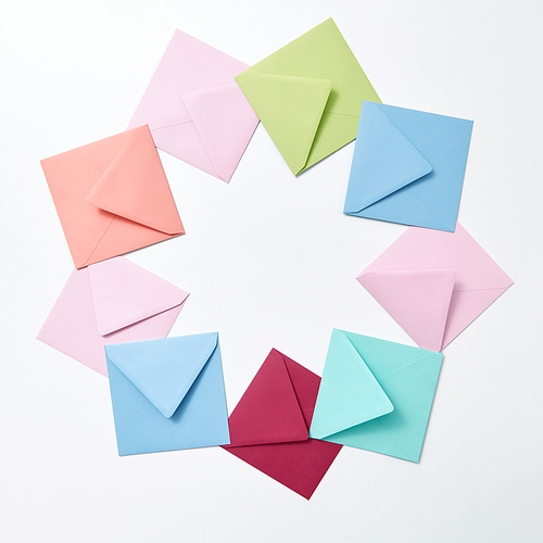 Empty colorful hndcraft envelopes in the shape of round frame on a light gray background with copy space.