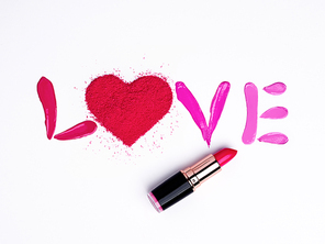 Valentine's Day background. Red and pink lipstick smeared in the shape of the letters love. Isolated on white background. Cosmetic products. Beauty and makeup concept