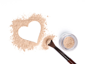 Valentine's Day background. Beige powder eye shadow scattered in the shape of heart. Isolated on white background. Cosmetic products