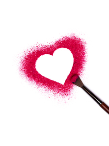 Valentine's Day background. Pink red powder eye shadow scattered in the shape of heart. Isolated on white background. Cosmetic products