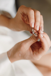 the bride is holding an engagement ring with precious stones in her hands