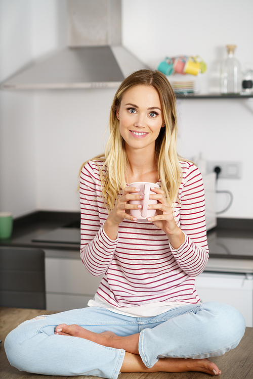 Smiling caucasian woman holding a cup of coffee at home.