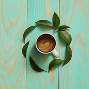 cup of black coffee and green leaves isolated on blue background. Flat lay