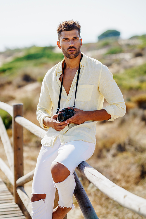 Handsome man photographing in a coastal area with an SLR camera