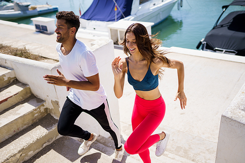 Athletic couple training hard by running up stairs together near the boats in a harbour