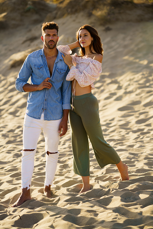 Young couple standing on the sand of the beach wearing casual clothes.