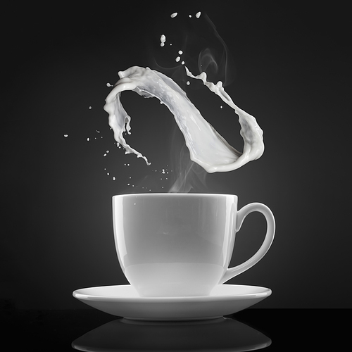 white cup with hot liquid and milk splash on black