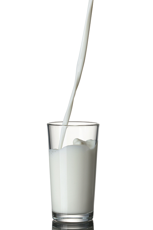 Milk pouring into the glass isolated on white